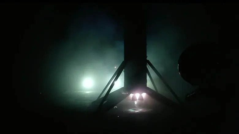 SpaceX Falcon 9 launches 29 Starlink satellites into low Earth orbit from Florida the first stage of an orbital rocket is seen in silhouette backlit by spotlights as it stands upright on its landing legs atop an ocean-based droneship